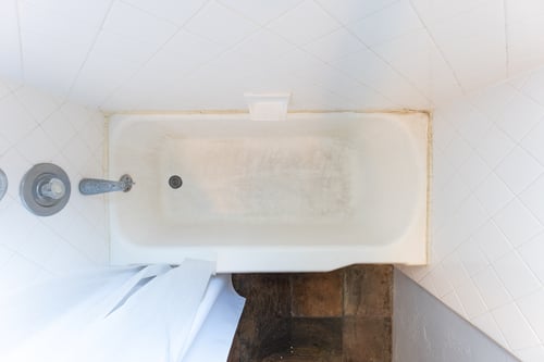 A bird's eye view of a dirty fiberglass tub with the base stained.