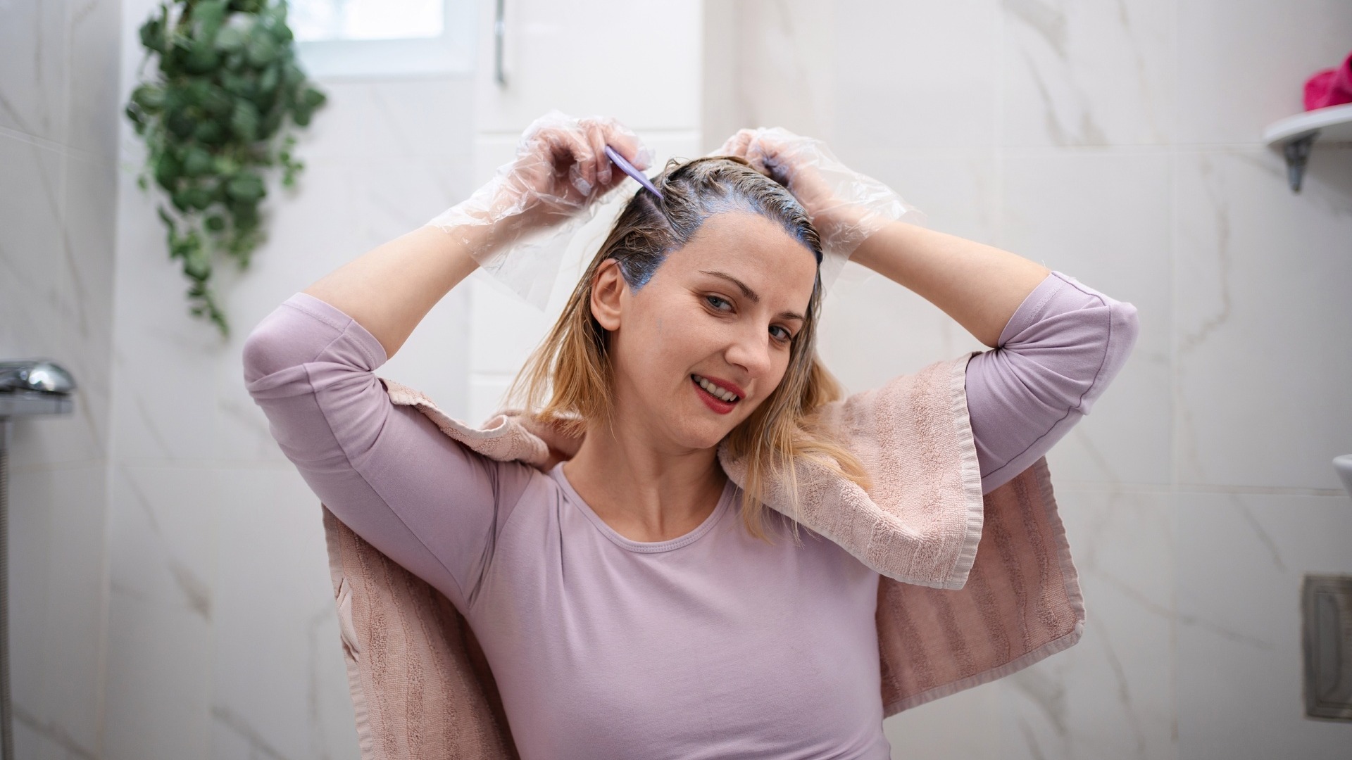 A woman dying her hair in the tub and shower area.