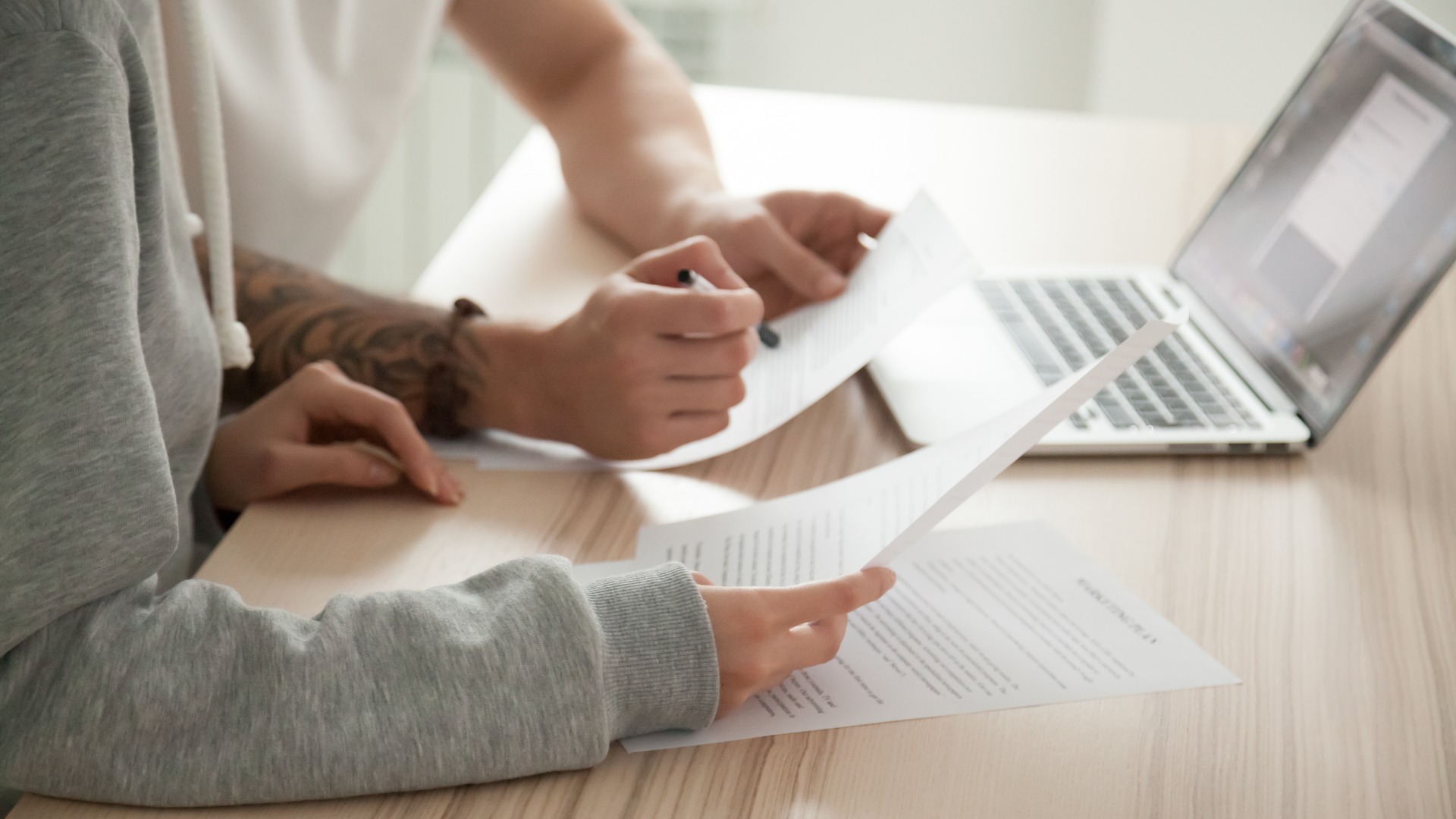 Two people sitting at a table and comparing remodeling contracts.