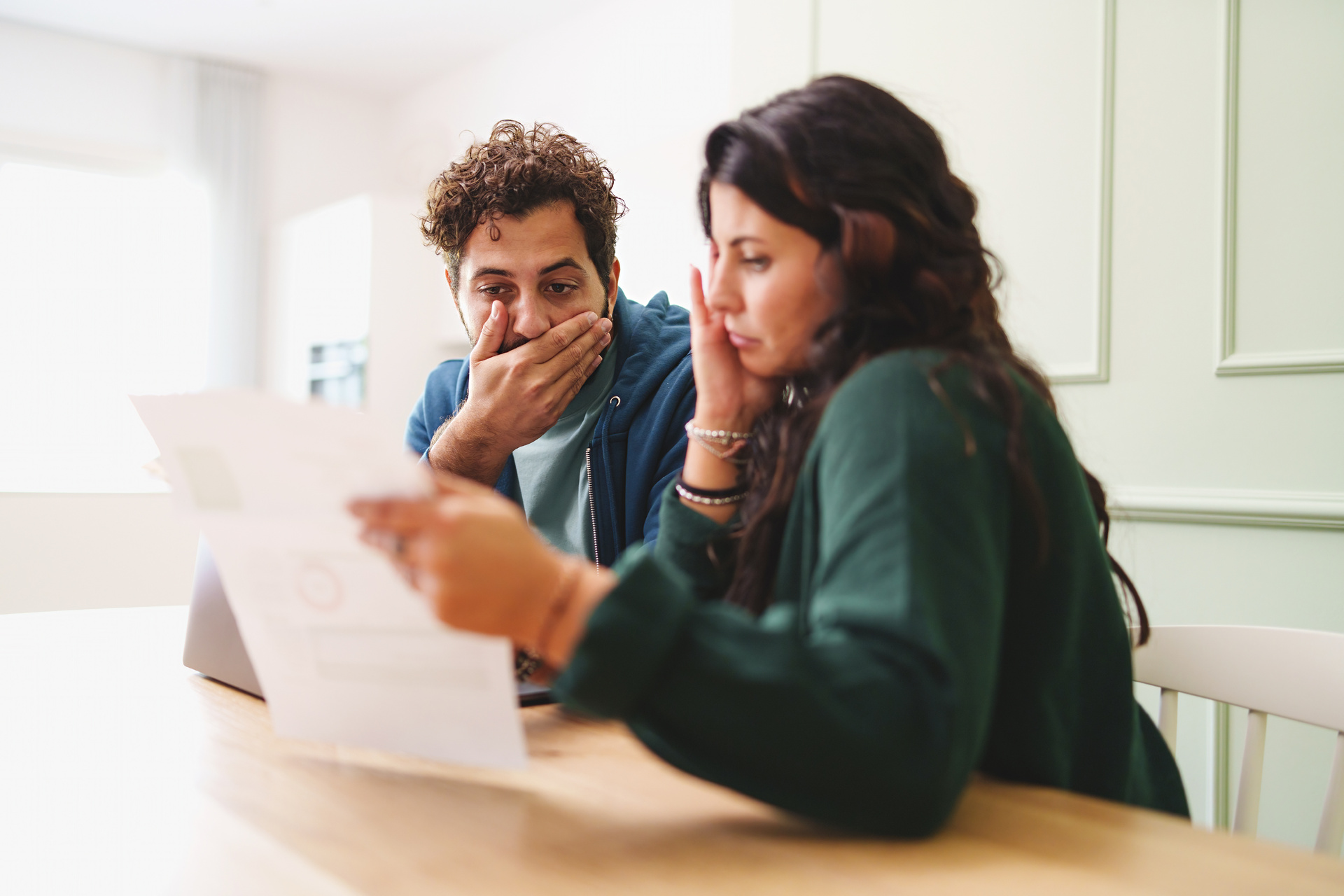 A man and a woman appear worried as they look at a bill.
