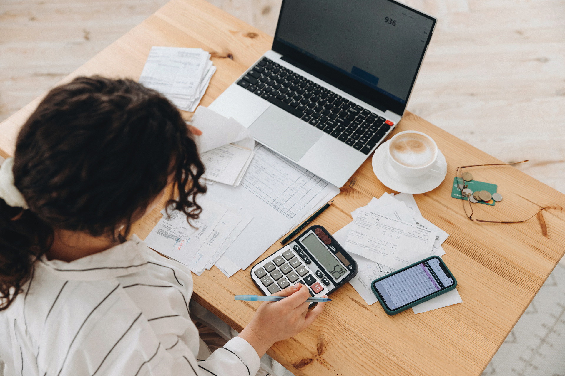 A woman at her desk using a calculator to budget for a shower remodel.