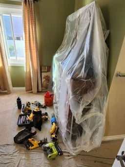 Inside of a home with furniture covered by plastic to prevent dust making a mess during a demolition.