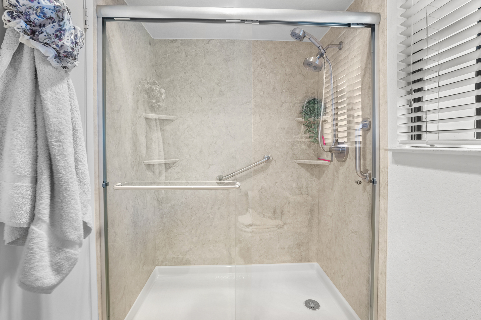 A shower with tavertine walls and a sliding glass door
