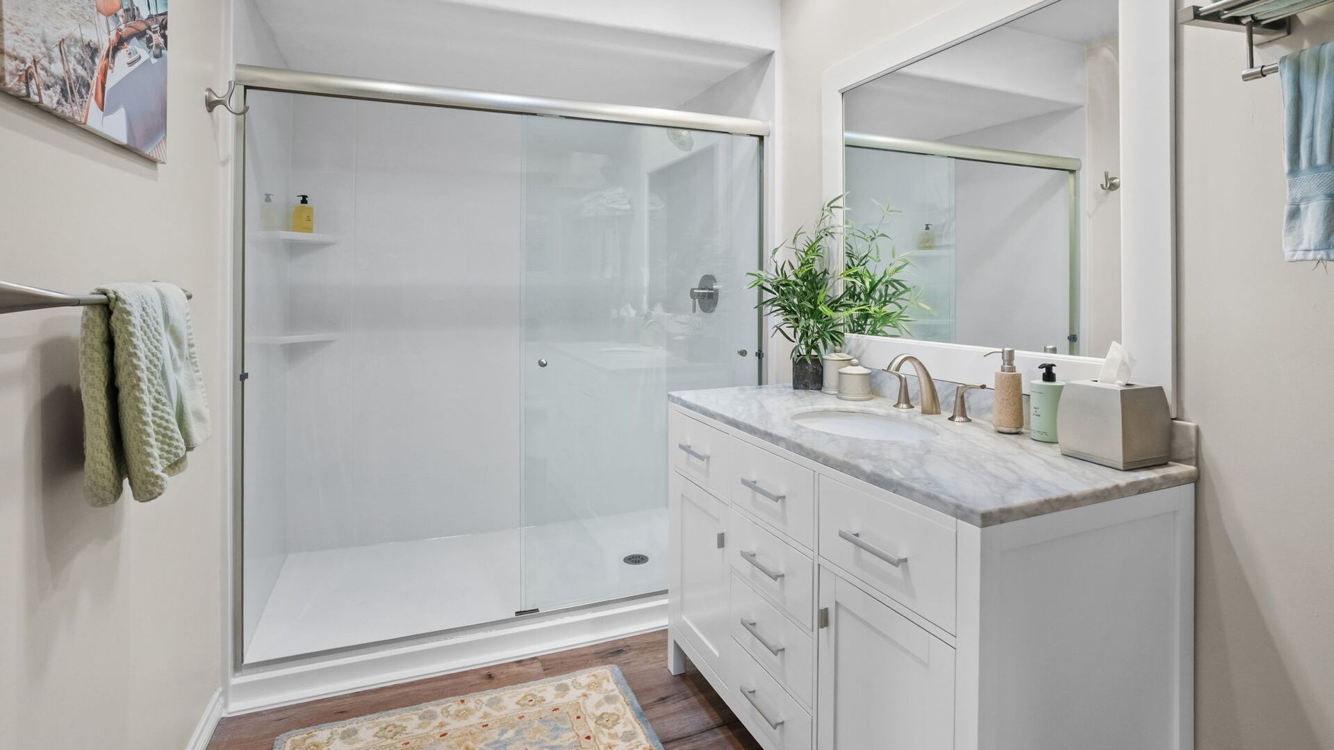 A newly installed white wall walk-in shower with two corner shelves and sliding glass doors.