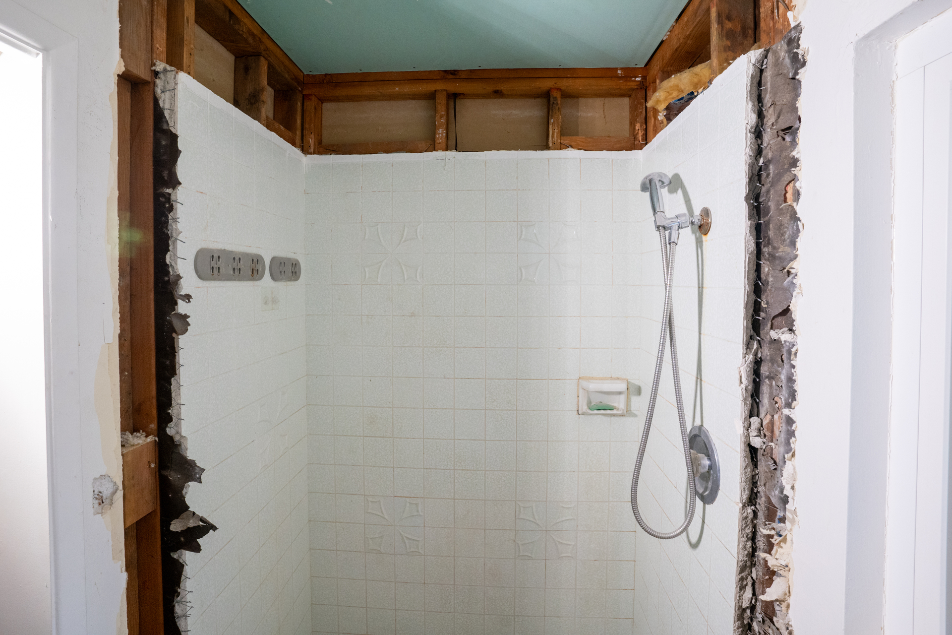 An old shower is being demoed, with the walls removed for a new remodel
