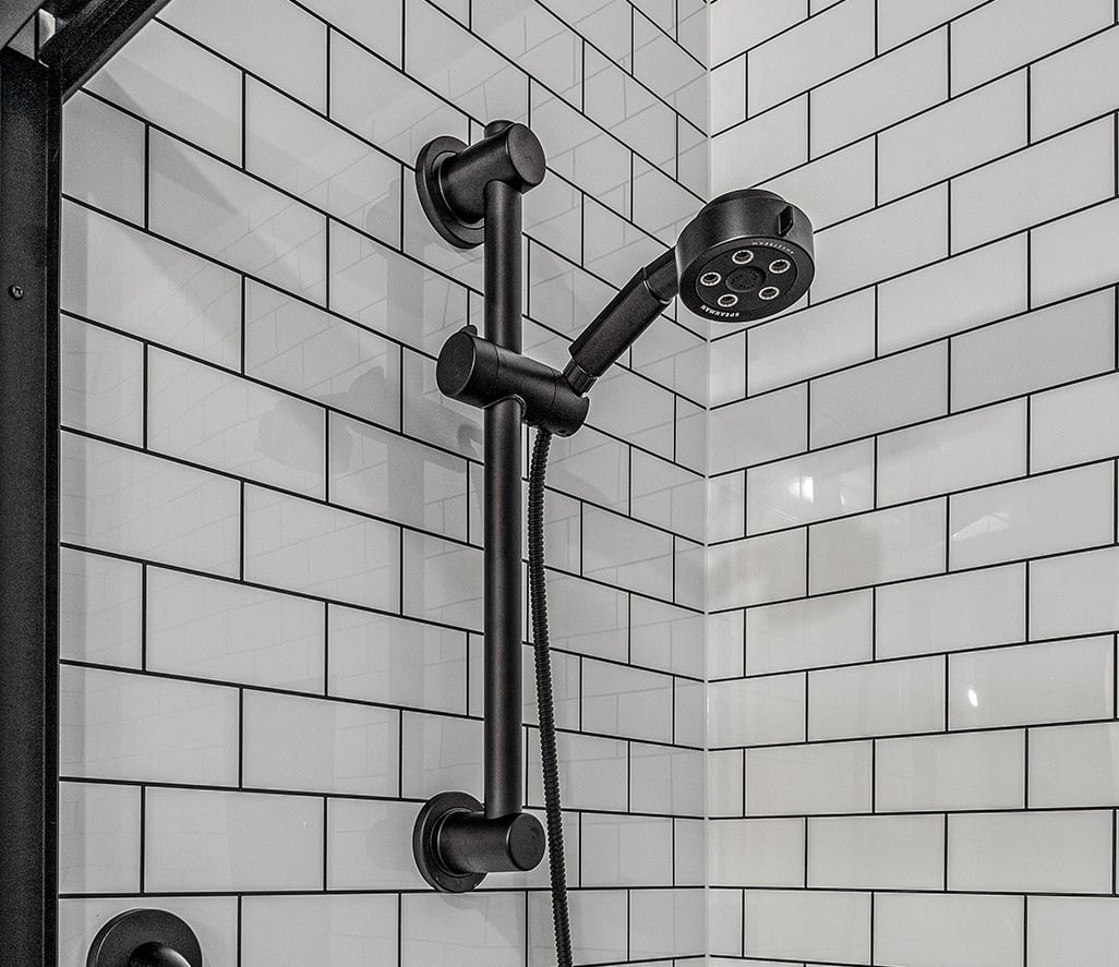 Black handheld shower head on a slidebar.