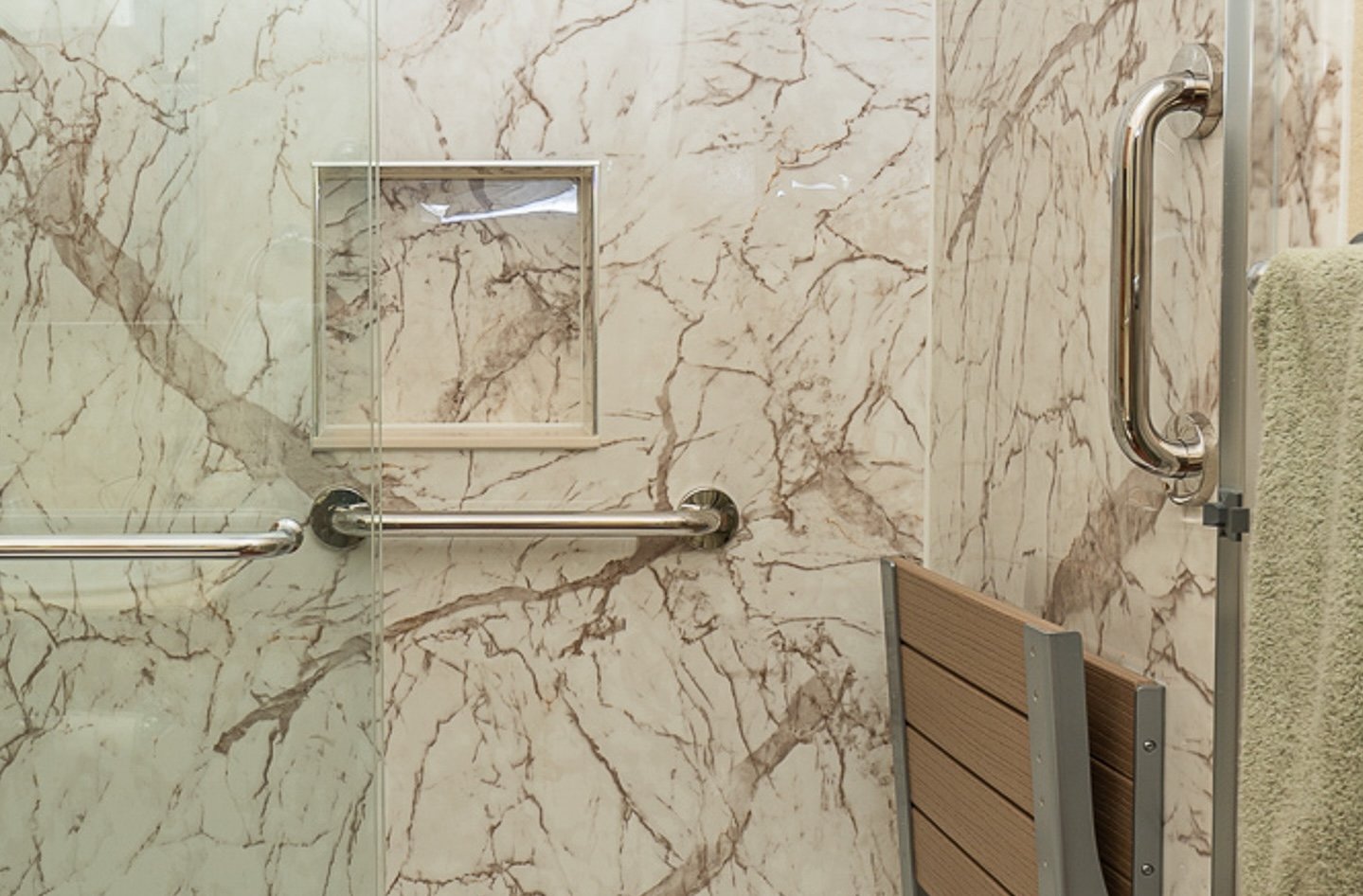 A shower with a storage niche, brushed nickel fixtures, and a seat