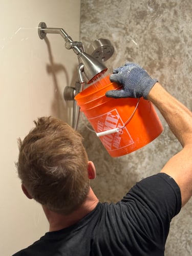 A shower installer is testing the water flow of a newly installed shower head.