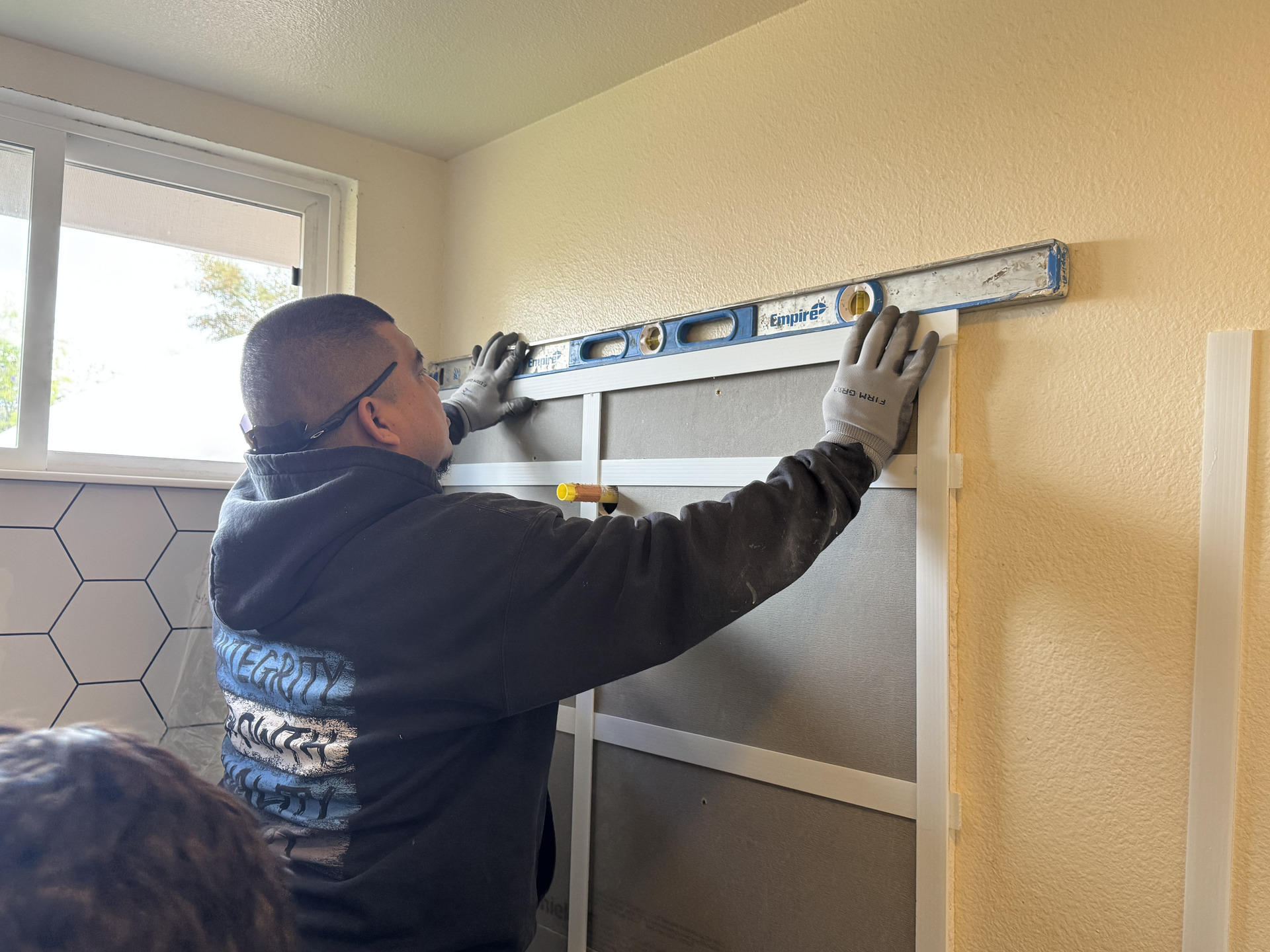 A professional shower installer leveling the inside of the area during a shower remodel.