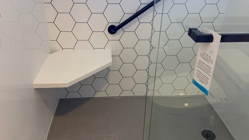 A built-in shower seat attached to a corner, accompanied by a grab bar for extra safety.