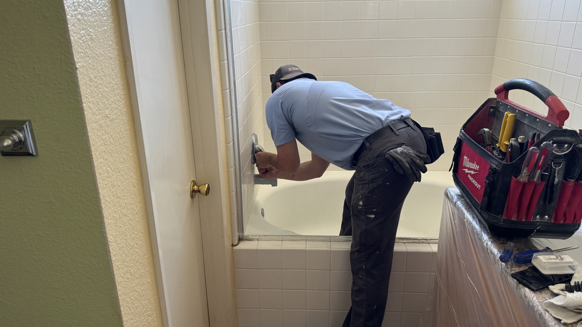 A Shugarman's Bath installer inspects a valve and prepares to demo an old tub and shower area.