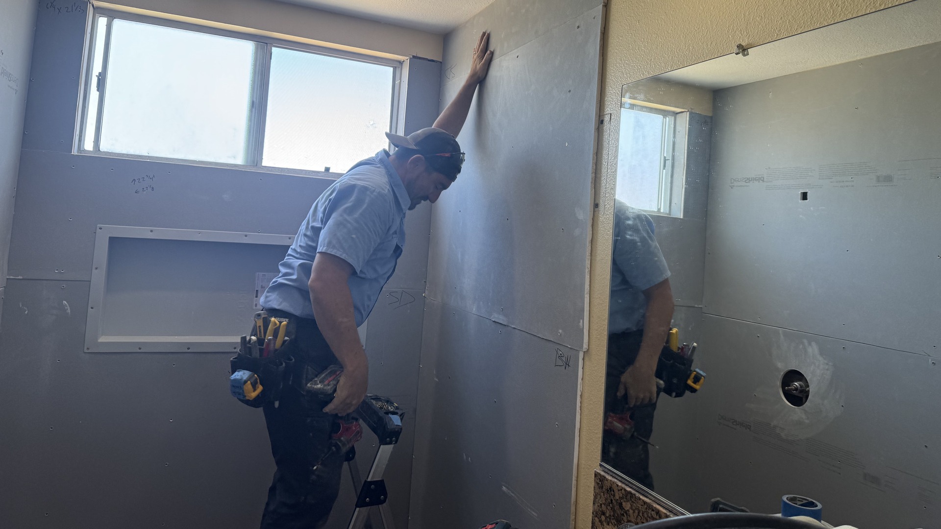 A shower installer in the process of applying DensShield Backer Board to waterproof.