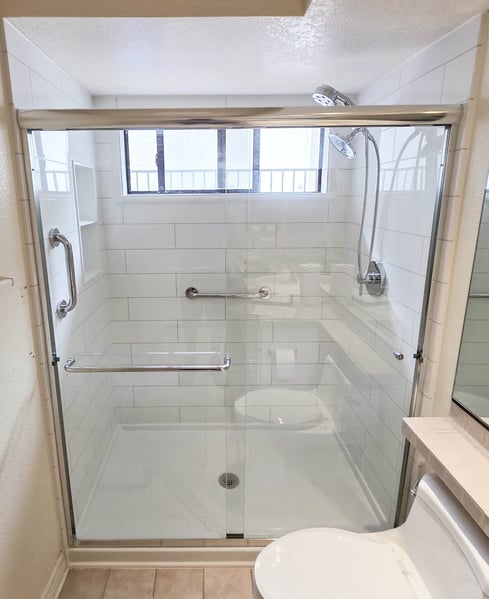 A walk-in shower with clear sliding glass doors