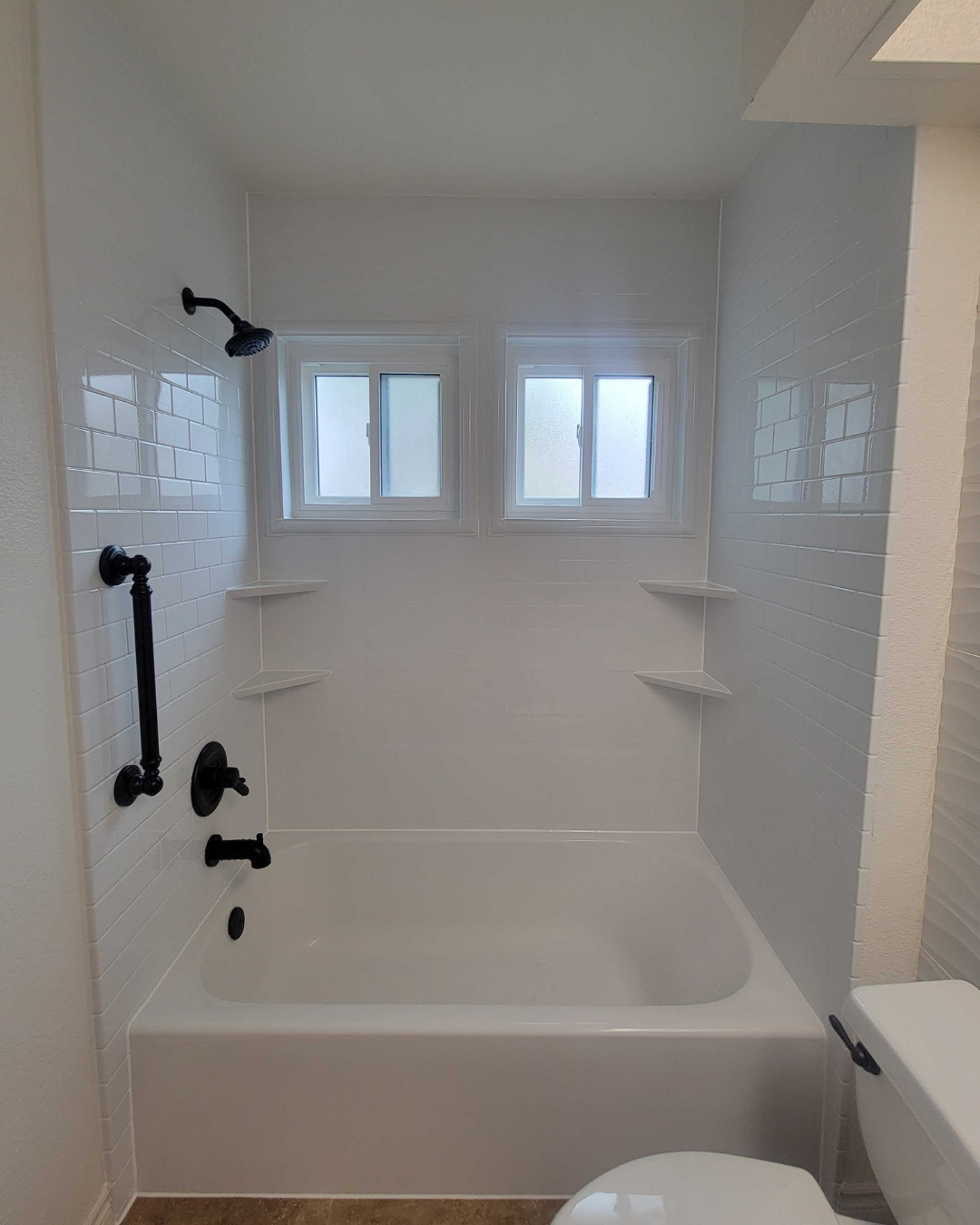 A remodeled traditional shower with a bathtub and four shower corner storage shelves