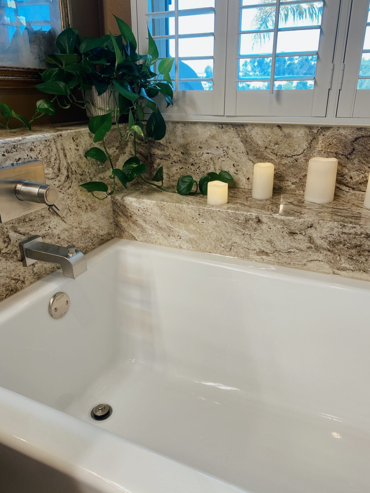 A bathtub remodel with five candles on the ledge above