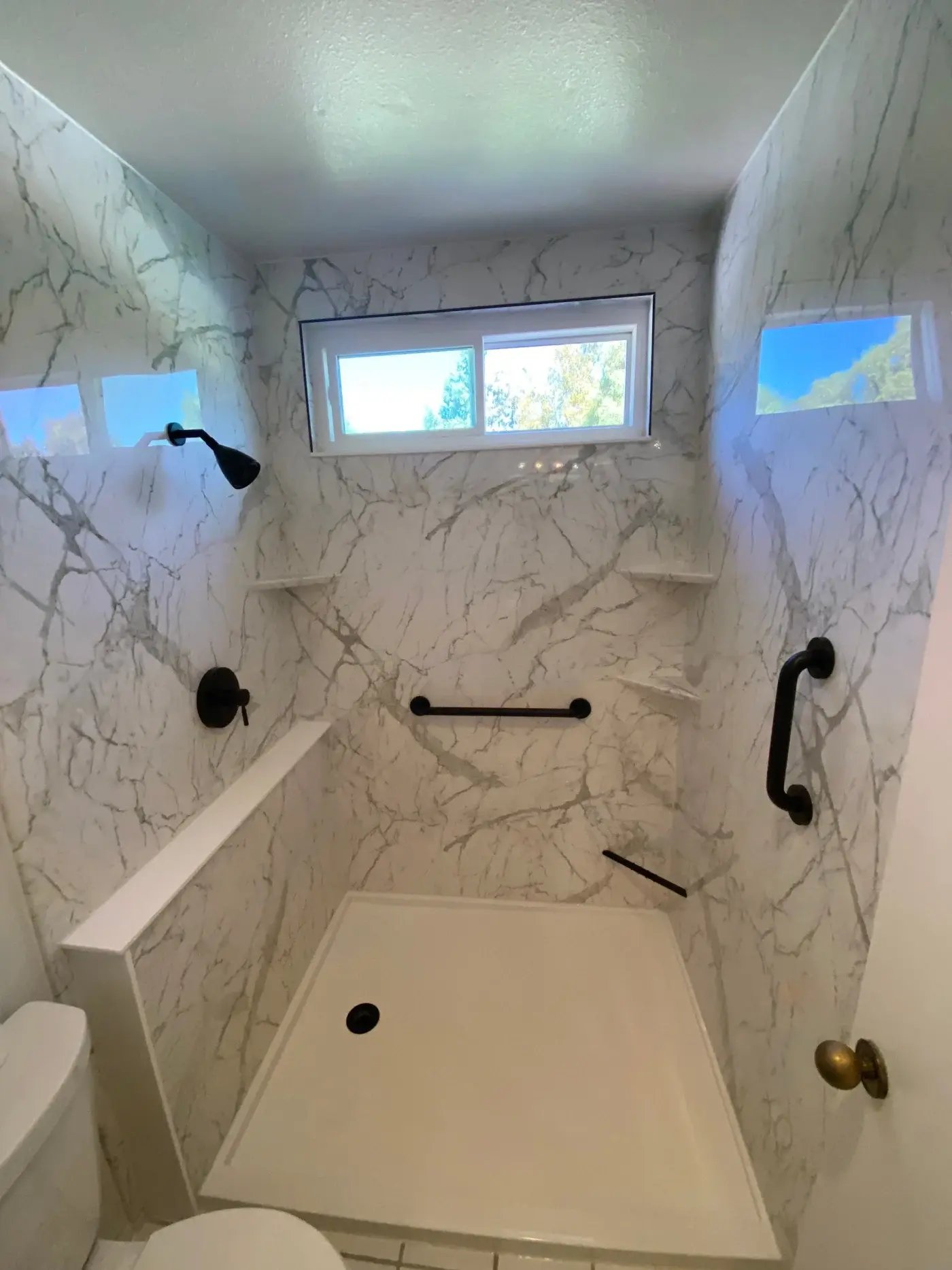 A new remodeled shower with two grab bars and three shower storage corners