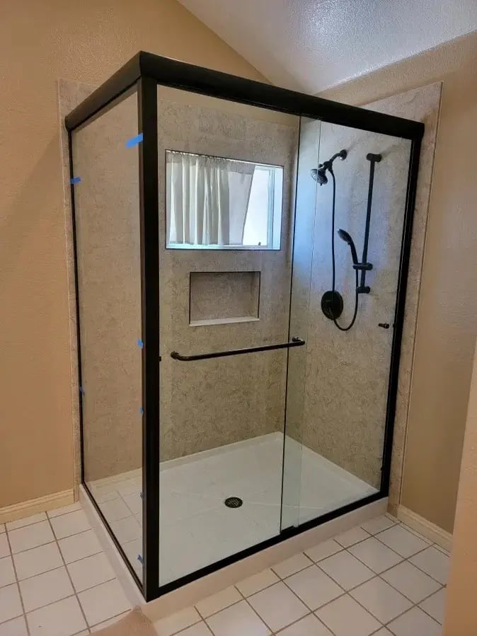 A remodeled rectangular walk-in shower with a shower storage niche and clear glass shower doors