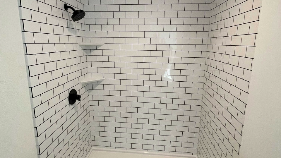 A shower remodel with two shower storage corner shelves