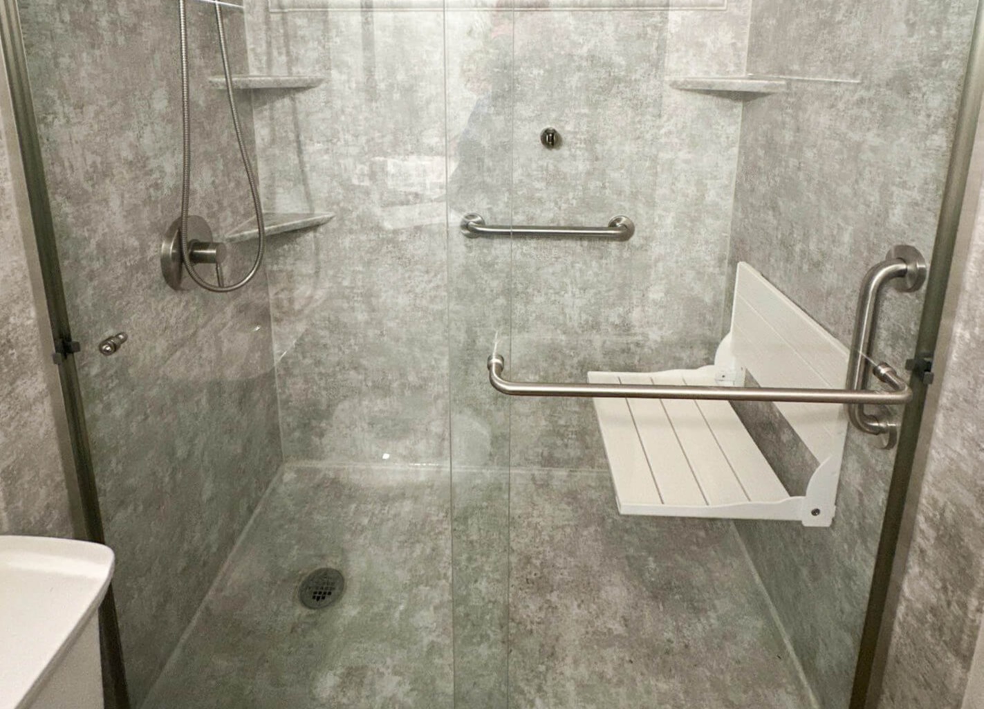 A shower remodel with a white composite folding shower seat.