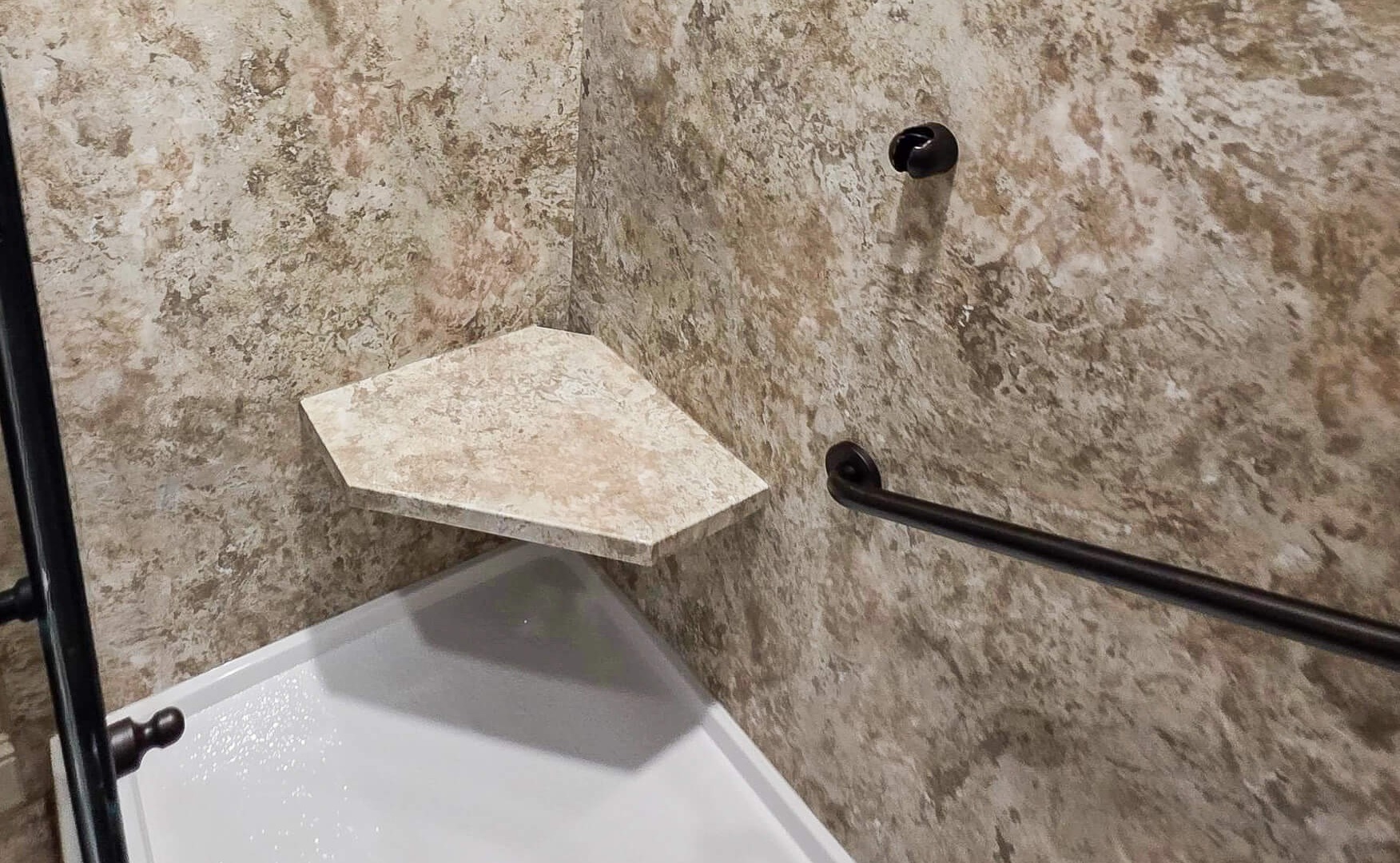 A bianco travertine corner shower seat in a walk-in shower.