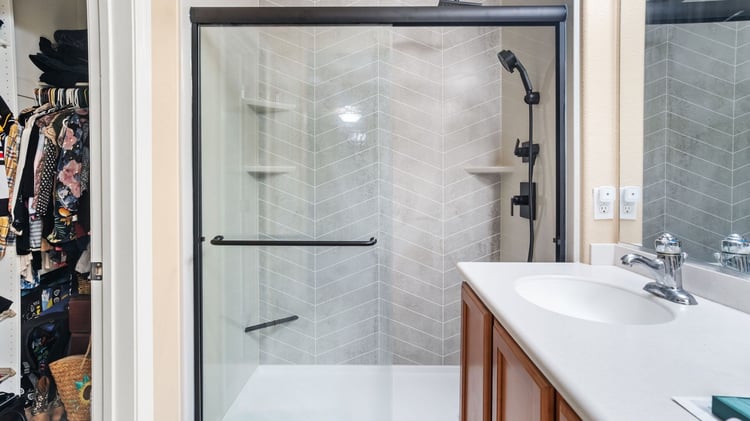 A walk-in shower with a handheld shower head and three corner shelves.