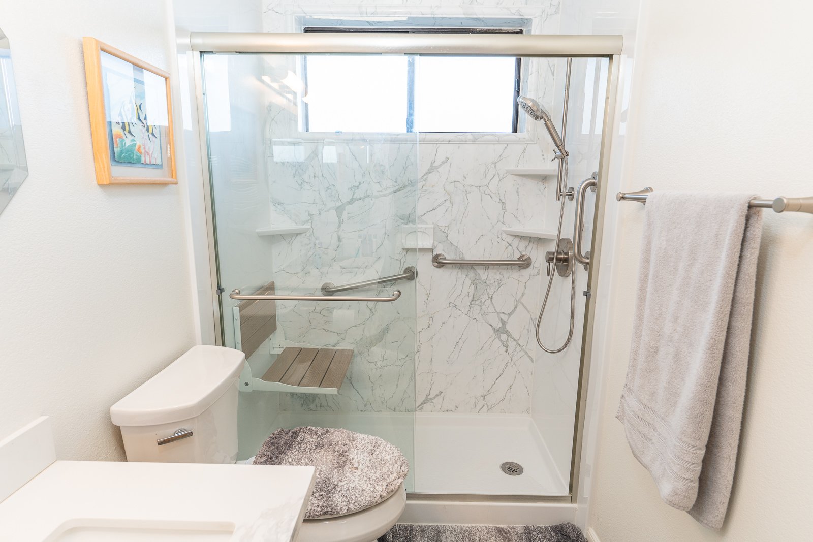 A new walk-in shower with a folding shower seat, a handheld shower head, and 3 grab bars.