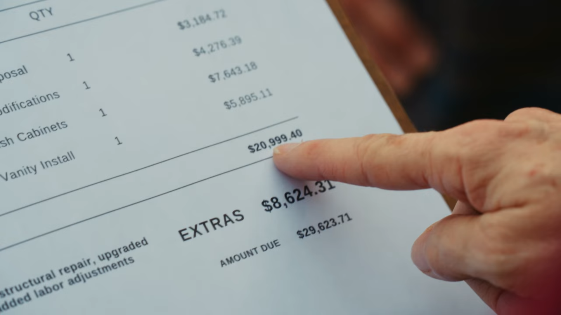 A hand pointing at a price on a contract.