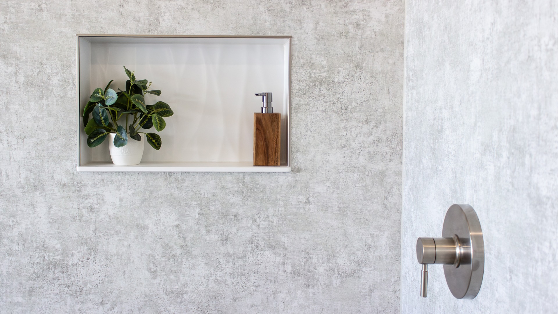 A shower storage niche with a plant and a pump bottle.