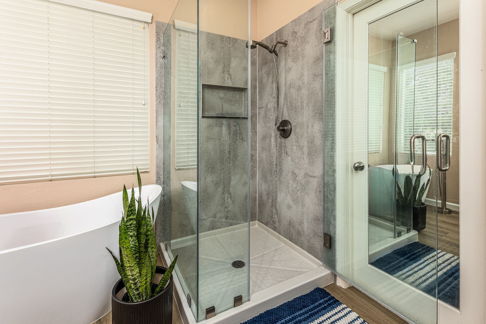 A remodeled bathroom with a Cali combo, which has a tub on the left and a new walk-in shower on the right in a glass enclosure.