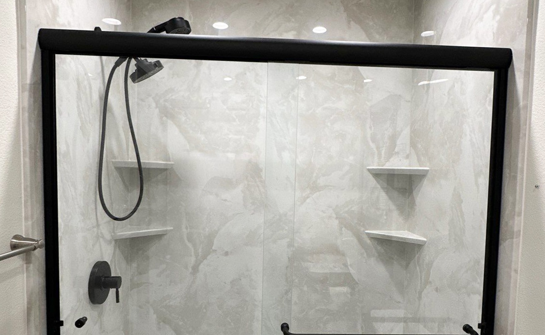 A brown wall walk-in shower with matte black colored fixtures