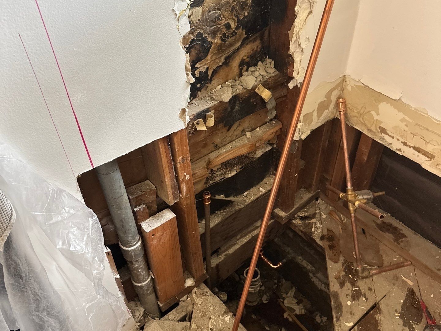 A demoed shower wall revealing a leak from defective plumbing.