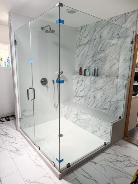 A remodeled walk-in shower with a clear glass enclosure and a custom shower seat