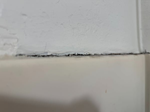 Cracked and separated silicone between the top of a shower and drywall