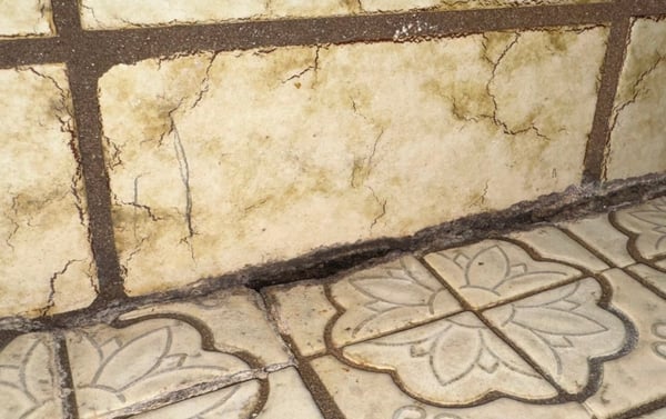 A cheaply done tile shower remodel with grout cracking at the seam between the base and wall