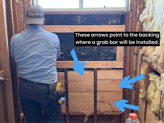 arrows pointing to wood backing where grab bars will be installed.
