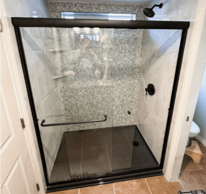 a walk-in shower with a fixed head and two corner storage shelves