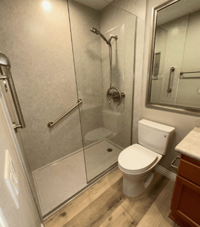 a walk-in shower with an onyx base, two grab bars, and a handheld shower head