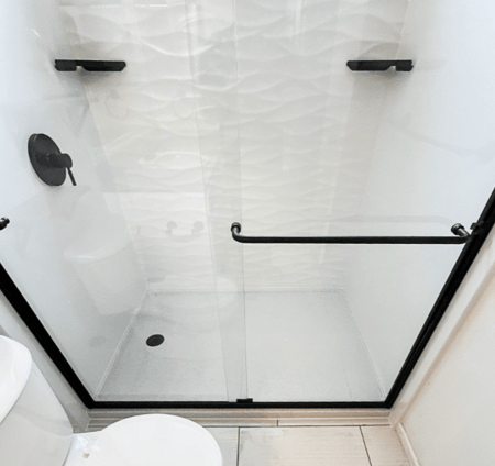 a new walk-in shower with scallop walls and matte black fixtures