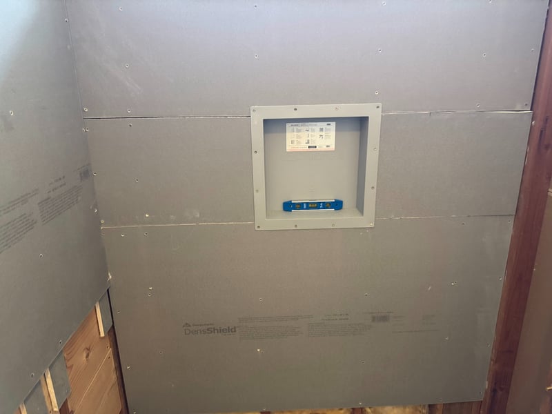 Installing a shower storage niche in a wall in the DensShield Backer Board. There is a leveler in the niche.
