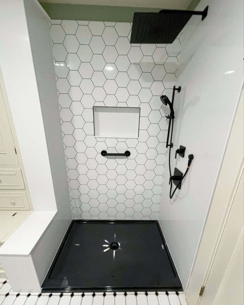 A walk-in shower with a hexagonal tile pattern accent wall