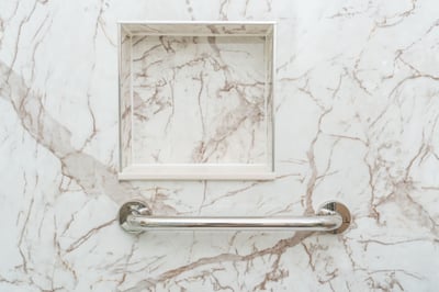 A shower with a grab bar and shower storage niche