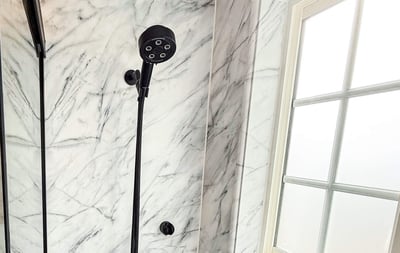 A Calcutta marble wall shower with matte black fixtures