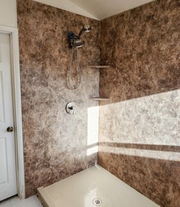 A walk-in shower with river rock colored walls