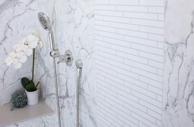 A Calcutta marble wall shower with a deco panel